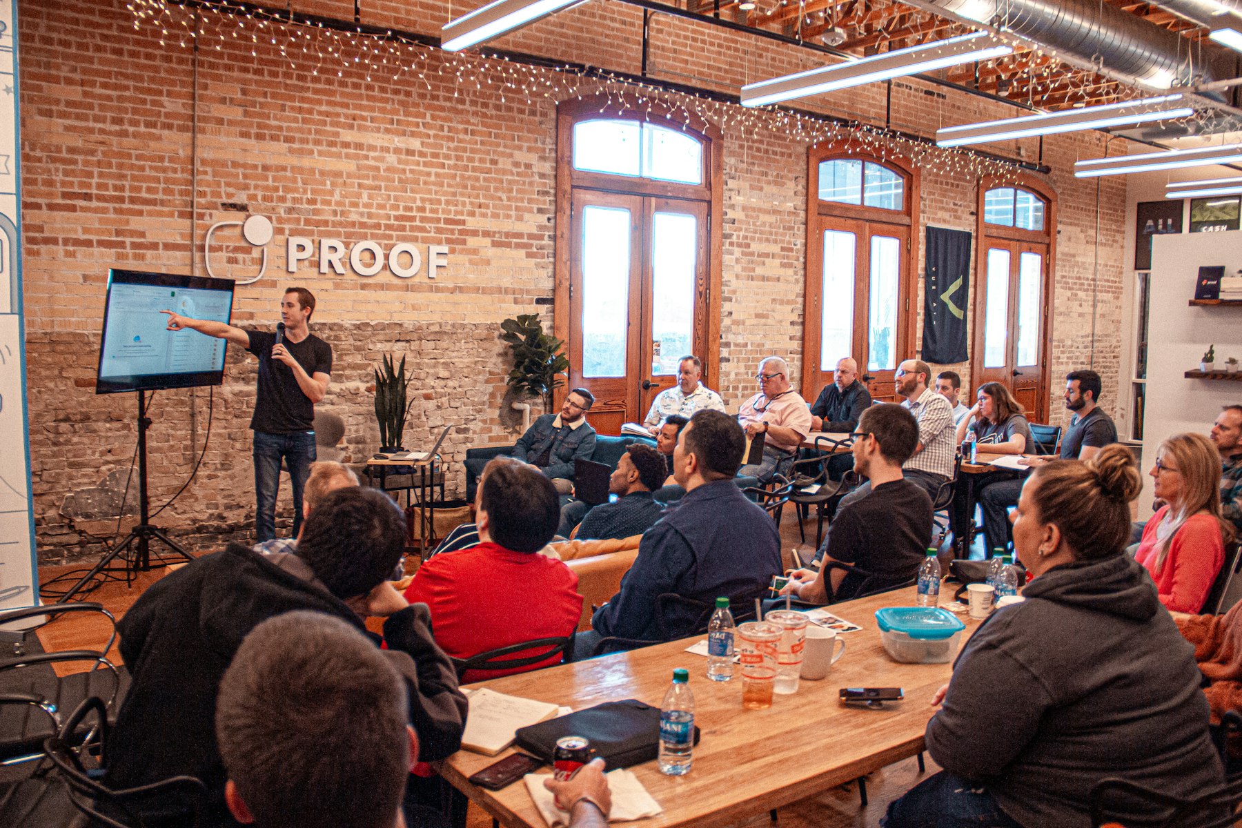 A speaker at a whiteboard in a brick-walled meetup space